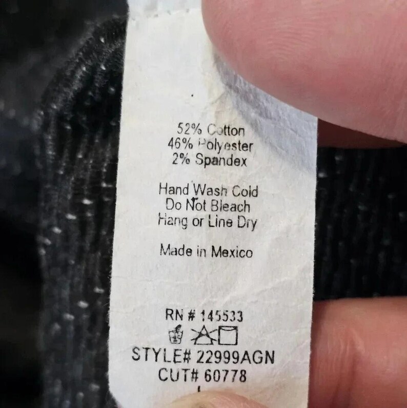 May include: A white clothing tag with black text. The tag lists fabric content as 52% cotton, 46% polyester, and 2% spandex. Washing instructions include hand wash cold, do not bleach, and hang or line dry. The tag is made in Mexico.
