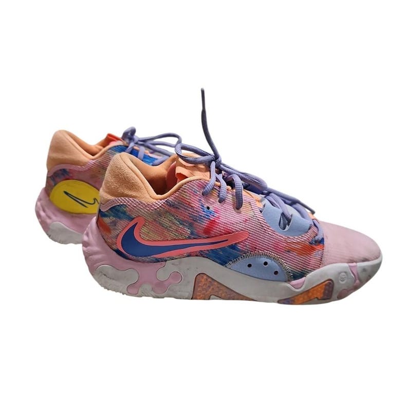 May include: Pair of colorful athletic shoes with a mix of pink, blue, and orange hues. The shoes feature a blue and pink swoosh logo, light purple laces, and a textured sole. The design includes a combination of patterns and colors.