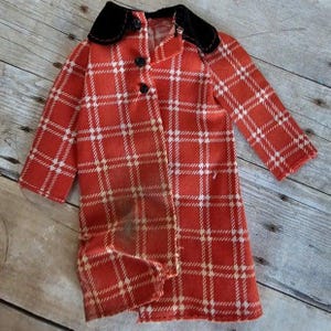 May include: A red and white plaid coat with a black velvet collar. The coat is made of a soft, fuzzy fabric and has a button closure.
