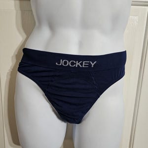 K&ouml;nnte beinhalten: Dunkelblaue Unterhose mit dem Wort "JOCKEY" in wei&szlig;en Buchstaben auf dem Bund. Die Unterhose ist aus einem weichen, leicht strukturierten Stoff gefertigt. Das Kleidungsst&uuml;ck wird auf einer wei&szlig;en Schaufensterpuppe pr&auml;sentiert.