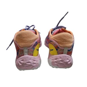 May include: Pair of colorful athletic shoes with a mix of pink, orange, and blue hues. The shoes feature a textured sole, a yellow accent, and the number "13" on the heel. The laces are a light purple color.