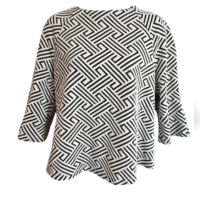 May include: A black and white geometric patterned sweater with three-quarter sleeves. The pattern consists of intersecting lines creating a maze-like design. The sweater has a round neckline and a slightly flared hem.