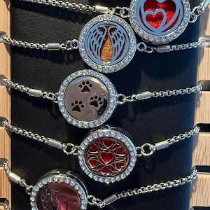 May include: Seven silver chain bracelets with round silver charms. The charms have different designs, including paw prints, hearts, wings, and a cat. The charms are decorated with rhinestones.