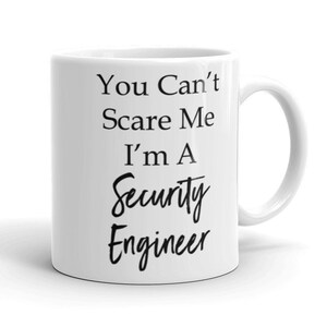 May include: White ceramic coffee mug with black text that reads "You Can't Scare Me I'm A Security Engineer".