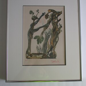 May include: A framed print of a surrealist artwork featuring a tree with intertwined branches and figures. The artwork is in shades of brown, green, and blue, with a white background. The print is signed "Dali" in the bottom right corner.