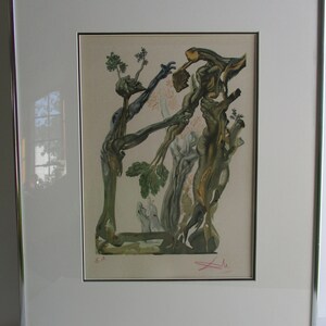May include: A framed print of a surrealist artwork depicting two figures intertwined with tree branches. The artwork is in shades of green, brown, and white, with a red signature in the bottom right corner. The print is numbered "E.A."