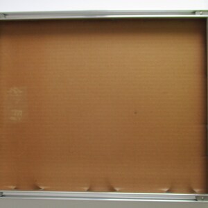 May include: A silver picture frame with a brown cardboard backing.