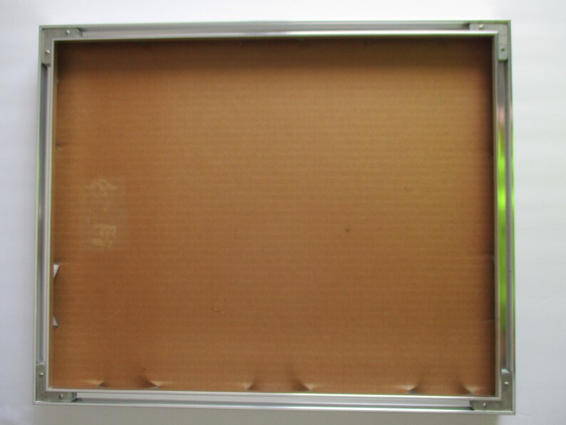 May include: A silver picture frame with a brown cardboard backing.