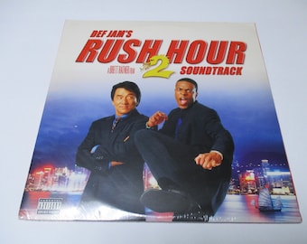 May include: A Def Jam's Rush Hour 2 soundtrack CD with a parental advisory sticker. The cover features Jackie Chan and Chris Tucker in a fighting pose against a backdrop of Hong Kong.