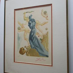 Pu&ograve; includere: Una stampa incorniciata di un dipinto surrealista che raffigura una figura in una veste blu in piedi su una scogliera con altre figure sullo sfondo. La stampa &egrave; firmata "Dal&iacute;" in basso a destra e include le iniziali "E.A." in basso a sinistra.