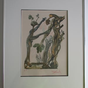 May include: A framed print of a surrealist artwork by Salvador Dali. The print features a complex composition of intertwined branches, figures, and a small dog. The artwork is rendered in shades of green, brown, and white, with a signature in the bottom right corner.