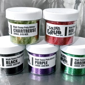 May include: Six small jars of high-temperature poly glitter in various colours: chartreuse, red, black, purple, green. Each jar has a label with the colour name, size, and "Golden Grub Lure Co."