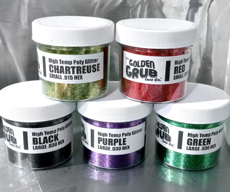 May include: Six small jars of high-temperature poly glitter in various colours: chartreuse, red, black, purple, green. Each jar has a label with the colour name, size, and "Golden Grub Lure Co."