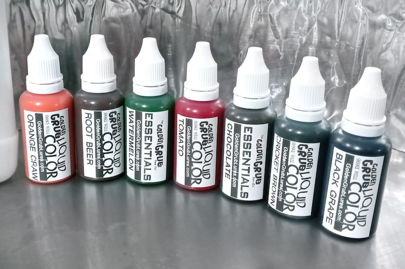 May include: Eight small bottles of liquid colour for use in crafting and art projects. The bottles are labelled with the colour names: Orange Craw, Root Beer, Watermelon, Tomato, Chocolate, Cricket Brown, Black Grape. Each bottle has a white cap and a label with the Golden Grub logo.