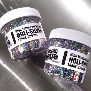 May include: Two jars of silver holographic glitter labeled "High Temp Poly Glitter HOLI-SILVER LARGE .030 HEX" with the brand name "Golden Grub Lure Co."