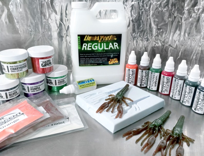 May include: A set of craft supplies for making fishing lures, including liquid plastic, glitter, colourants, and a mould for a crawfish lure. The set also includes a bottle of pure and unscented oil. The text on the bottle of liquid plastic reads "Liquid Plastic Regular Formula".