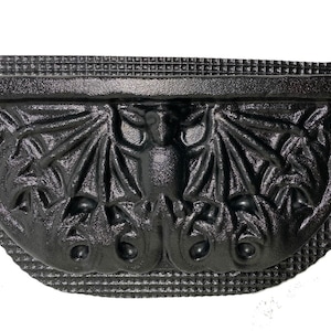 May include: Black plastic mold for making concrete garden decor. The mold is shaped like a bat with wings spread out. The mold has a textured surface and a smooth, flat back.