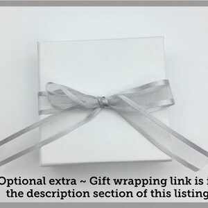 May include: A white gift box with a silver ribbon tied in a bow.