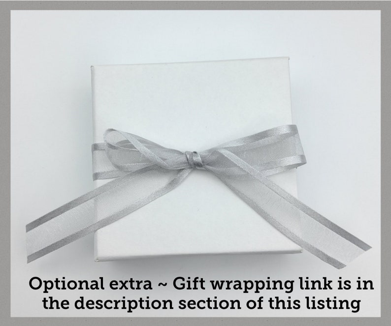 May include: A white gift box with a silver ribbon tied in a bow.