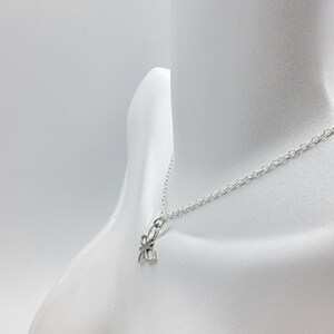May include: A silver chain necklace with a small, silver, four-leaf clover pendant.