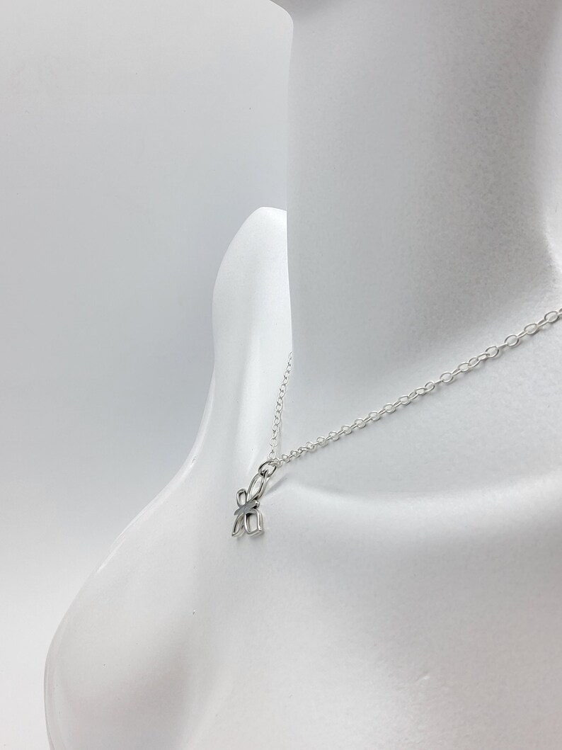 May include: A silver chain necklace with a small, silver, four-leaf clover pendant.