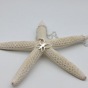 May include: A silver butterfly pendant necklace on a white starfish. The pendant is a delicate, openwork design.