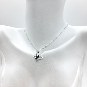 May include: A silver chain necklace with a delicate butterfly pendant. The butterfly is made of a single piece of metal and has a simple, elegant design.