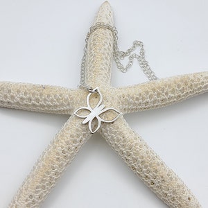 May include: A silver butterfly pendant necklace on a white starfish background.