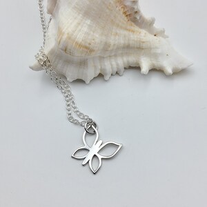 May include: A silver chain necklace with a delicate butterfly pendant. The pendant is a simple outline of a butterfly with open wings.
