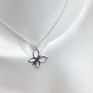 May include: A silver chain necklace with a delicate butterfly pendant. The butterfly is made of metal and has a cutout design.