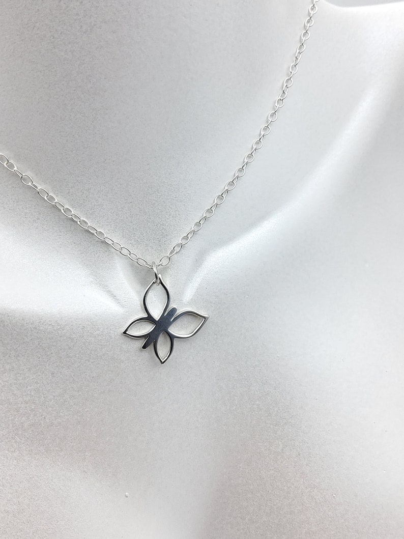 May include: A silver chain necklace with a delicate butterfly pendant. The butterfly is made of metal and has a cutout design.