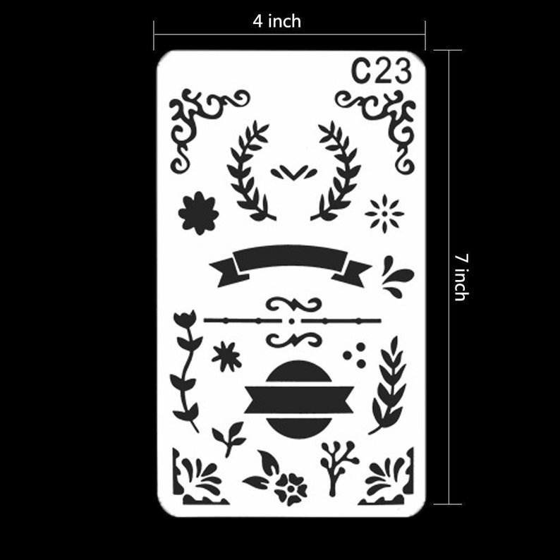 May include: A white stencil featuring black decorative designs, including floral elements, banners, and flourishes. The stencil measures 10 cm wide and 18 cm long, with the text "C23" in the upper right corner.