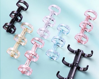 Puede incluir: Surtido de anillos de encuadernación de plástico de colores y metal negro. Los anillos son de varios colores, incluyendo rosa, azul, amarillo y negro. Los anillos están diseñados para sujetar juntos papeles o páginas sueltos.