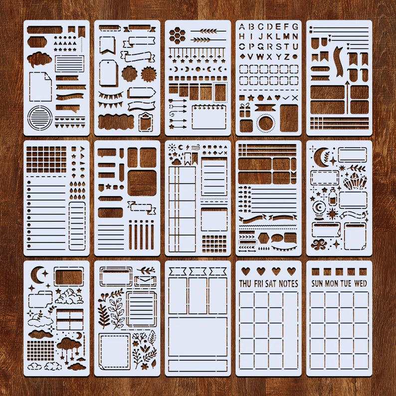 Puede incluir: Un conjunto de plantillas de pl&aacute;stico blanco con varios dise&ntilde;os, incluyendo pancartas, nubes y formas geom&eacute;tricas. Algunas plantillas presentan letras y dise&ntilde;os de calendario. Las plantillas est&aacute;n dispuestas sobre una superficie de madera marr&oacute;n.
