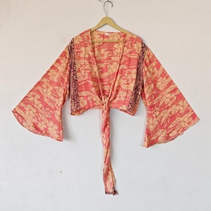 May include: A pink and yellow floral print kimono top with long bell sleeves and a tie closure at the waist.