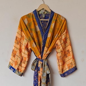 May include: A long, yellow, blue and green patterned silk robe with a sash tie. The robe has a floral print and a geometric pattern.