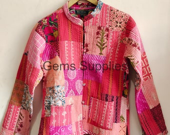 May include: A pink quilted jacket with a mandarin collar and a button closure. The jacket is made of patchwork fabric with different floral and geometric patterns. The label "Ravaliya" is visible on the front of the jacket.