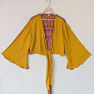 May include: A yellow silk kimono with a floral pattern and a tie at the waist. The kimono has long sleeves and a V-neck.
