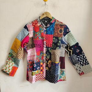 Może przedstawiać: Kolorowa pikowana kurtka w stylu patchwork z kołnierzem mandaryńskim i długimi rękawami. Kurtka jest wykonana z różnych tkanin o różnych wzorach i kolorach, w tym kwiatowych, geometrycznych i paisley.
