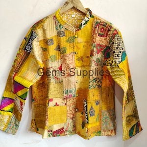 May include: A yellow quilted jacket with a patchwork design featuring various colors and patterns. The jacket has a mandarin collar and a button closure.