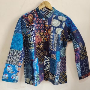 May include: A blue and black patchwork quilted jacket with a mandarin collar and long sleeves. The jacket is made of a variety of fabrics with different patterns and textures.