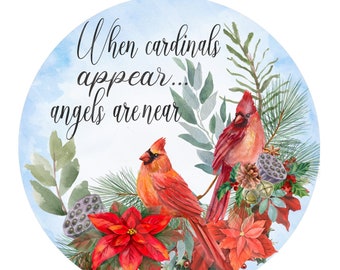 Könnte beinhalten: Ein Aquarellbild von zwei roten Kardinälen, die auf einem Zweig mit grünen Blättern und roten Weihnachtssternen sitzen. Der Text "When cardinals appear... angels are near" ist in einer kursivschriftlichen Schriftart geschrieben.
