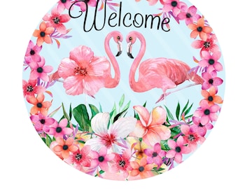 Pode incluir: Placa redonda com um design em aquarela com dois flamingos cor-de-rosa voltados um para o outro, rodeados por flores rosa e laranja e folhas verdes. A palavra "Welcome" está escrita em itálico no topo.