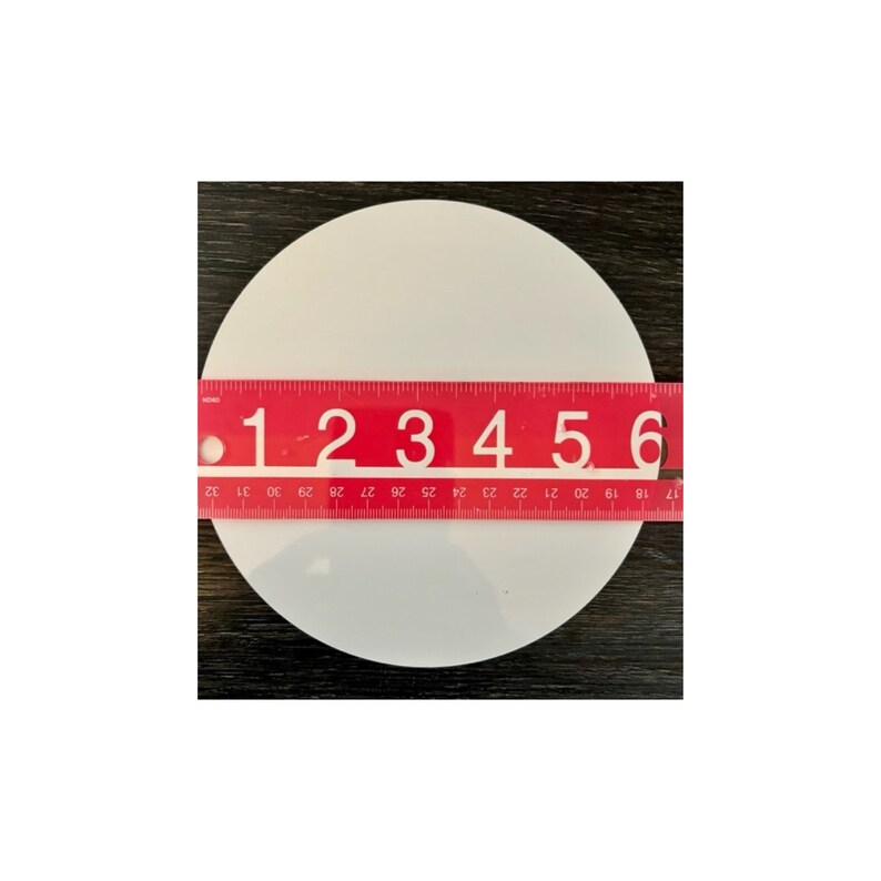 May include: A white ceramic circle with a diameter of 6 inches. The circle is on a dark wood surface.