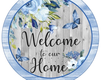 May include: A round wooden sign with a blue and white floral design and butterflies. The sign says "Welcome to our Home".