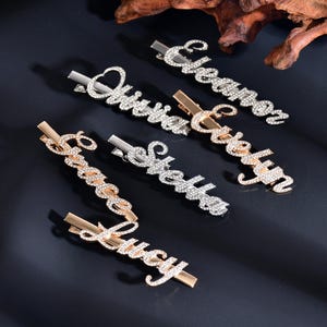 May include: Five silver and gold hair clips with rhinestones spelling out the names "Christian", "Evelyn", "Stephanie", "Grace Lucy", and "Elizabeth".