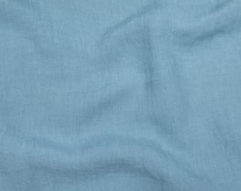 May include: A close-up shot of a light blue fabric with a slightly wrinkled texture. The fabric appears to be linen or a similar material, with subtle variations in color and tone across its surface.