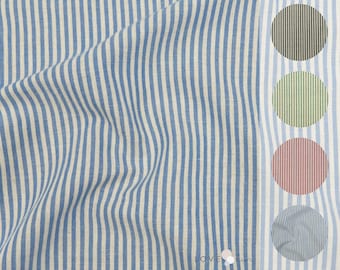 Può includere: Tessuto a righe blu e bianche con una sottile trama di lino. Il tessuto è piegato e drappeggiato, mostrando il motivo e la trama.