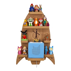 May include: A wooden rocket ship shelf with multiple shelves, featuring various cartoon characters and a blue speaker. The shelf is designed to be mounted on a wall.