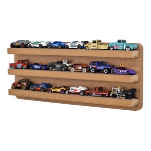 May include: A three-tiered, light brown wooden shelf displaying a collection of toy cars. The cars are various colours and styles, including trucks, sports cars, and race cars. The shelf is mounted on a white background.